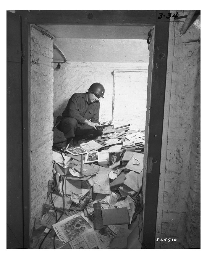 A US soldier inspects piles of Nazi books, including Mein Kampf,  that were found in a German school. [LCID: p971]